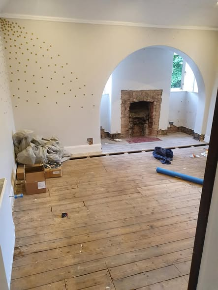 Living room with floorboards lifted for pipework access during a plumbing job in Stockport